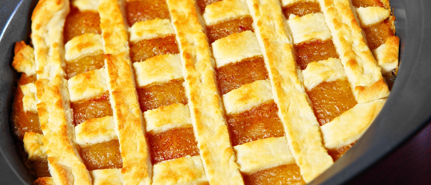 Zelfgemaakte linzenvlaai met abrikozenvulling en een raster van goudbruin deeg.