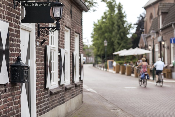 Bordje van een B&B in Geijsteren met fietsers op de achtergrond