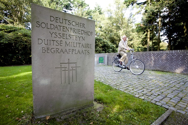 Oudere man fiets weg van de Duitse Oorlogsbegraafplaats in Ysselsteyn