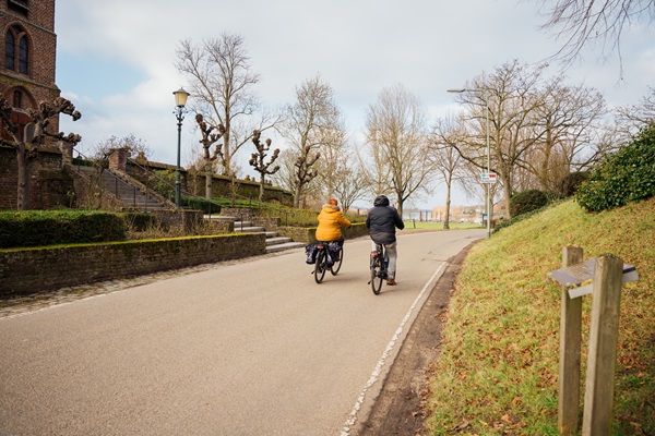 Zwei Radfahrer radeln im Herbst an der Rosenkirche in Asselt vorbei