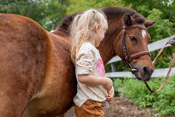 Girl stands by her pony