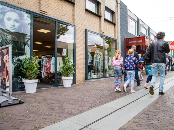 Säcke mit Kleidung stehen neben den Beinen von Frauen, die Einkaufen in Venray waren