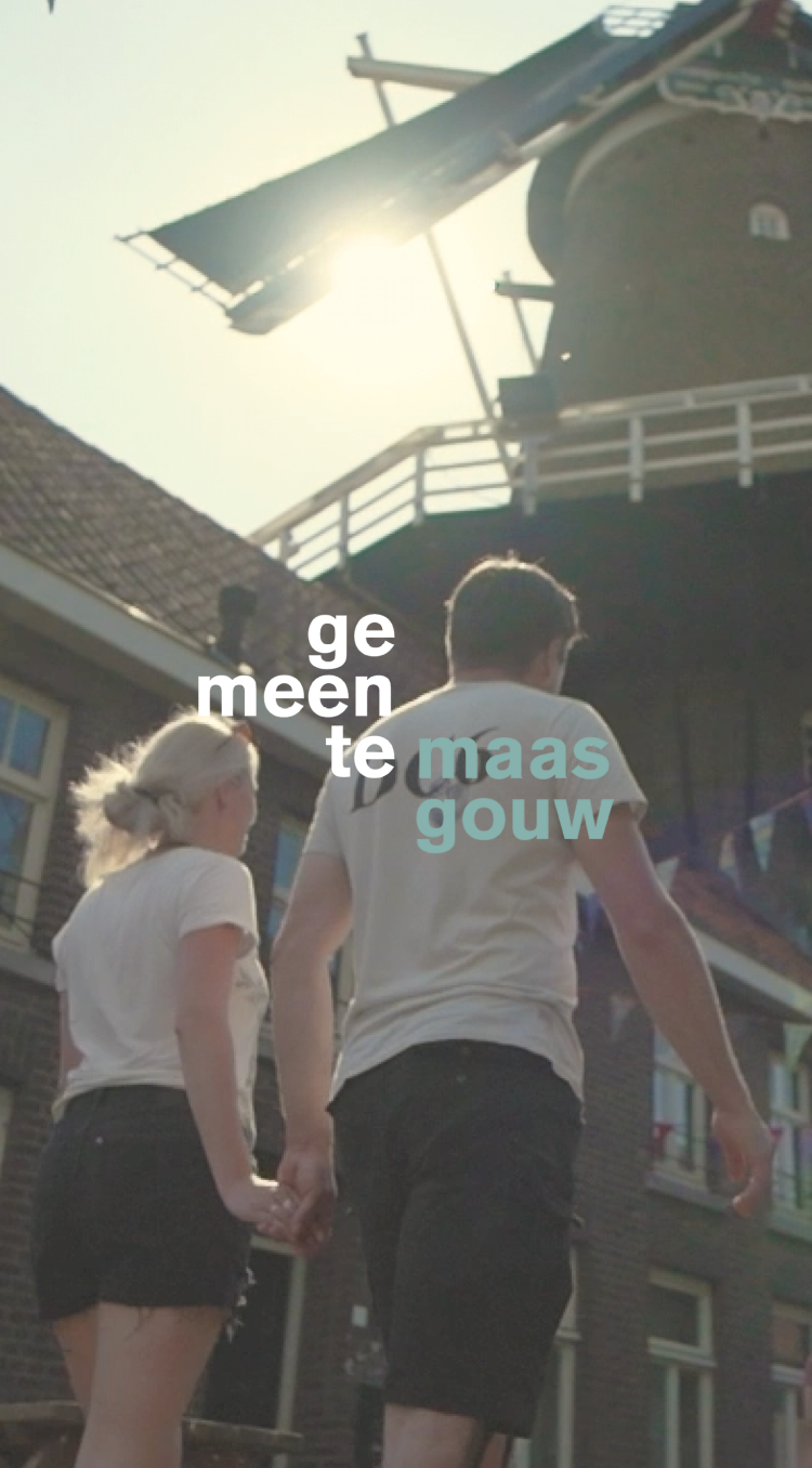 man en vrouw wandelen hand in hand langs de Hompesche Molen terwijl door de wieken schijnt