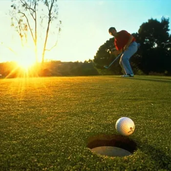 Golfer slaat een bal bij zonsondergang op de golfbaan van Golf & Countryclub Geijsteren in Limburg.