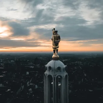 Standbeeld van Sint-Christoffel boven op de Sint-Christoffelkathedraal in Roermond, met uitzicht over de stad bij zonsondergang.